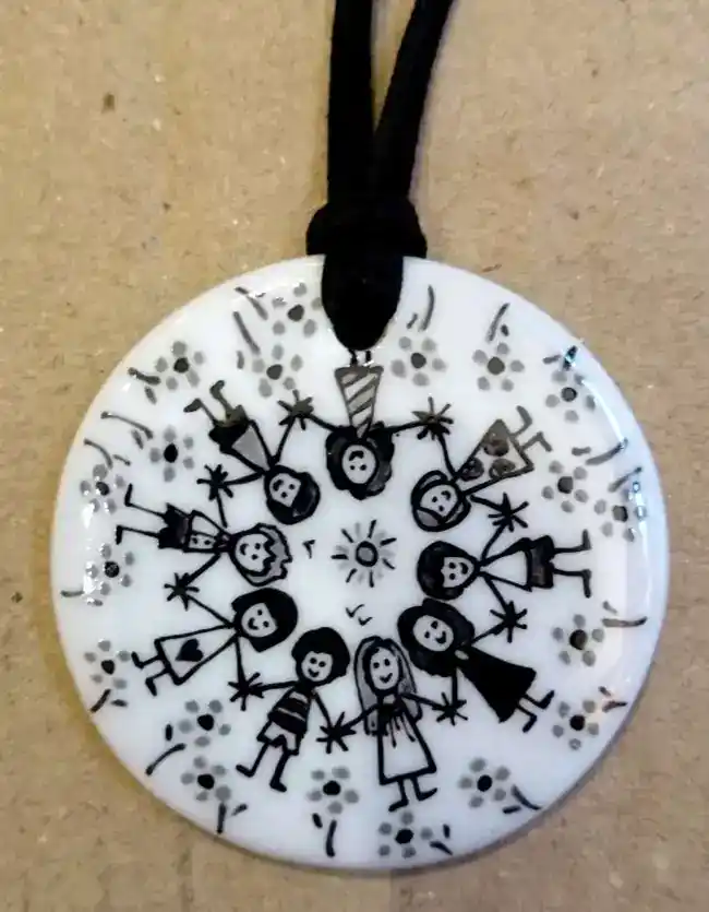 Pendentif rond en porcelaine personnalisé par une frise d'enfants en noir et gris