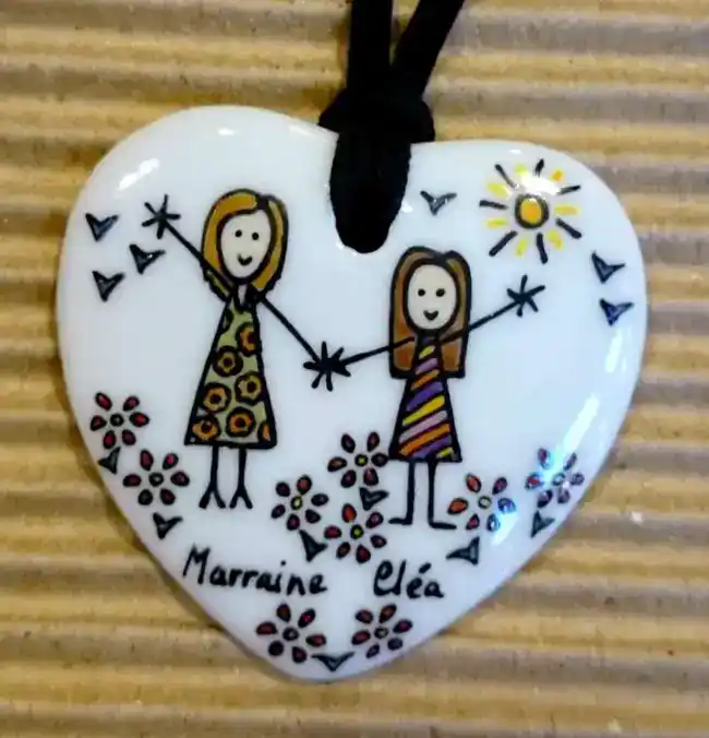 Pendentif coeur en porcelaine personnalisé dans un style naïf par une marraine et sa filleule.