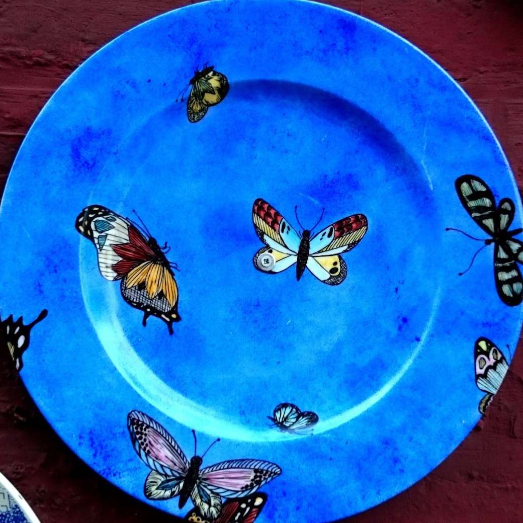 Assiette plate Hélène en porcelaine personnalisée par des papillons sur un fond bleu.
